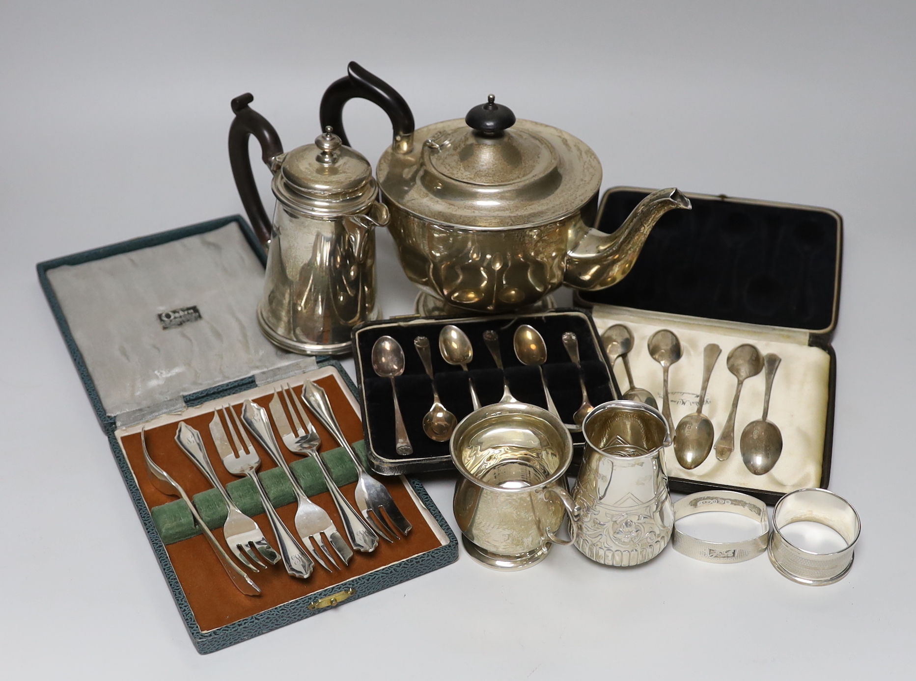 A mixed collection of silver items to include a George V teapot by Viners Ltd, a hot water pot, Victorian cream jug. christening mug, napkin rings and cased sets of teaspoons and pastry forks.